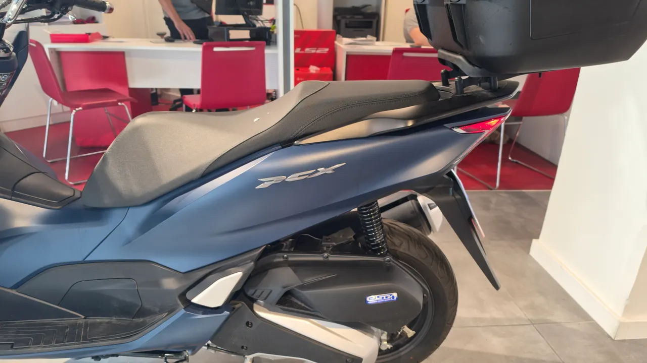 Vista lateral de una Honda PCX 125 azul mate con maletero negro