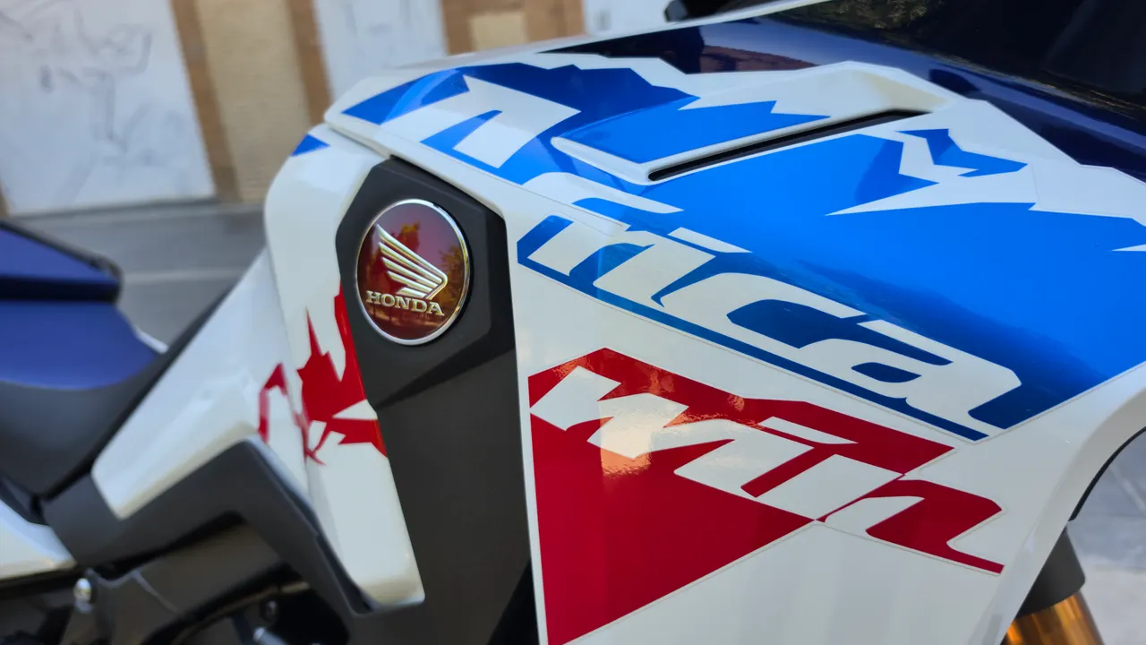 Detalle del lateral de la Honda Africa Twin CRF1100L blanca con gráficos azules y rojos