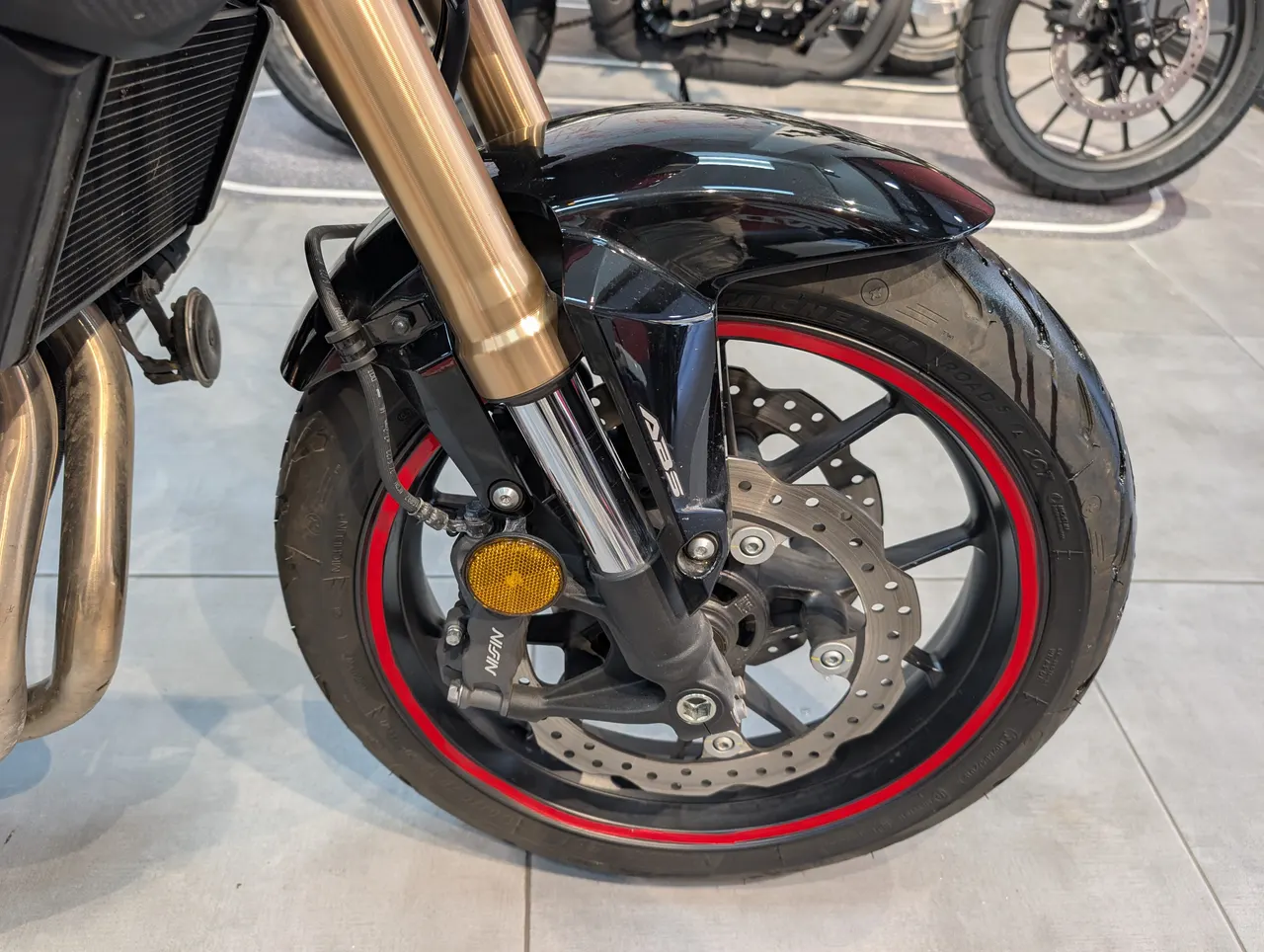 Detalle de la rueda delantera de una moto Honda CB500F negra con llanta roja.