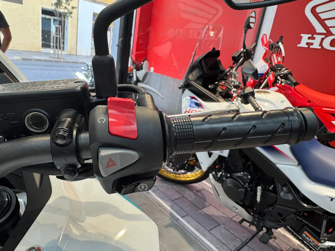 Manillar derecho de la Honda NX500 E-Clutch en color blanco, con puño, interruptor de encendido y luces de emergencia.