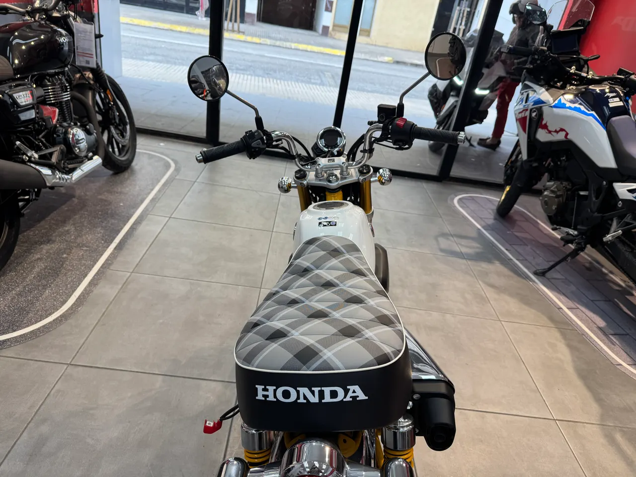 Honda Monkey amarilla con asiento a cuadros en exposición