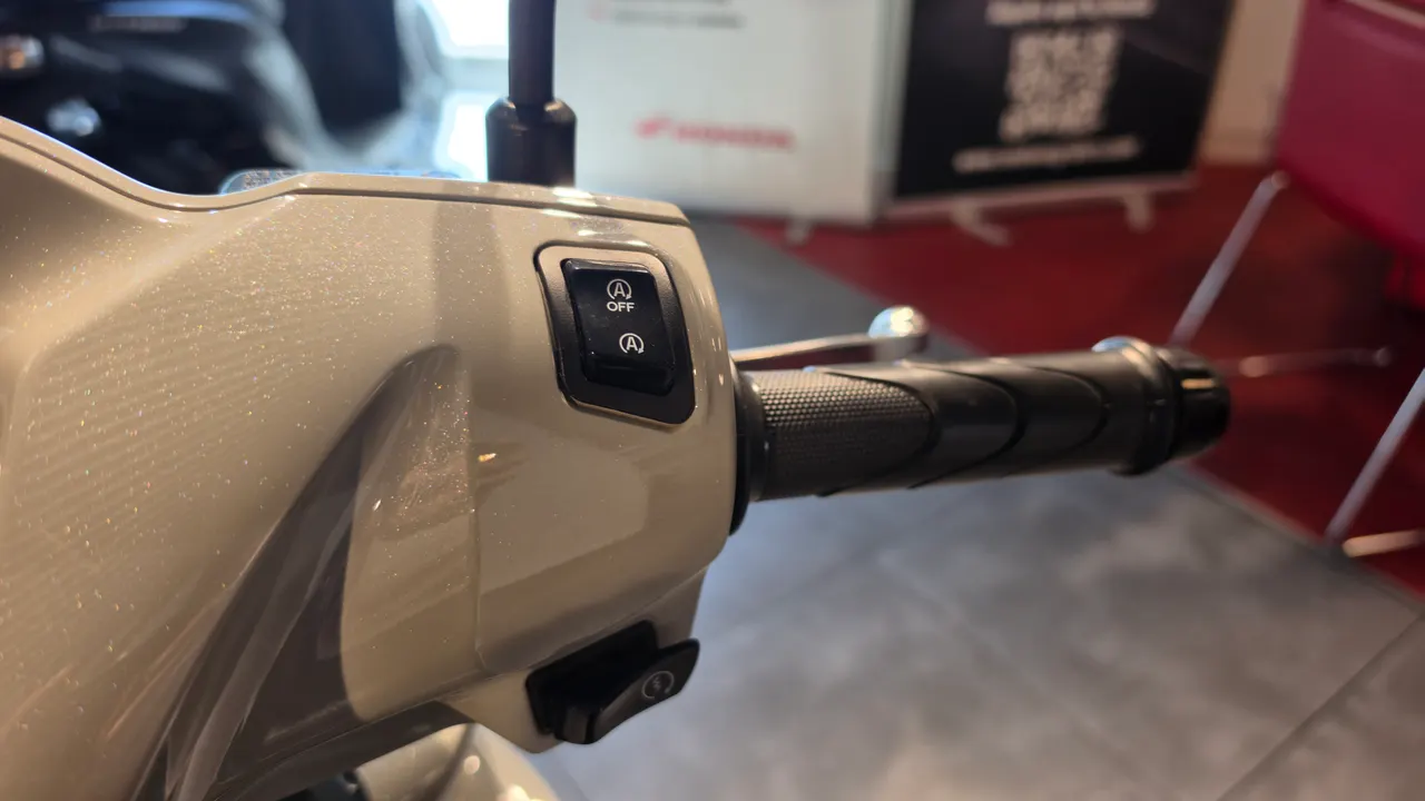Detalle del manillar y la botonera de una Honda Vision 110 en color blanco perla.