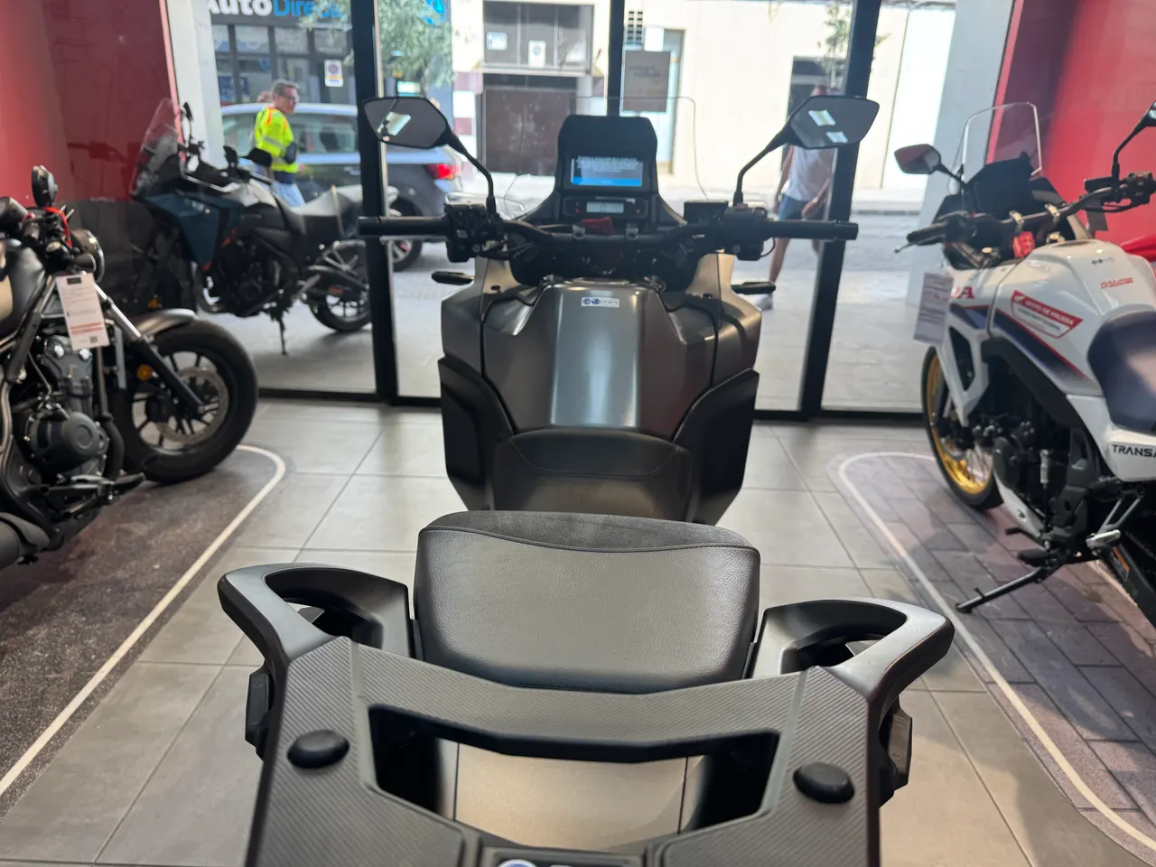 Vista frontal de una scooter gris en un concesionario de motos