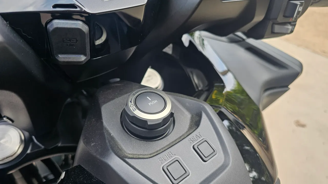 Panel de control central de la Honda Forza 750 negra con botones de combustible y asiento