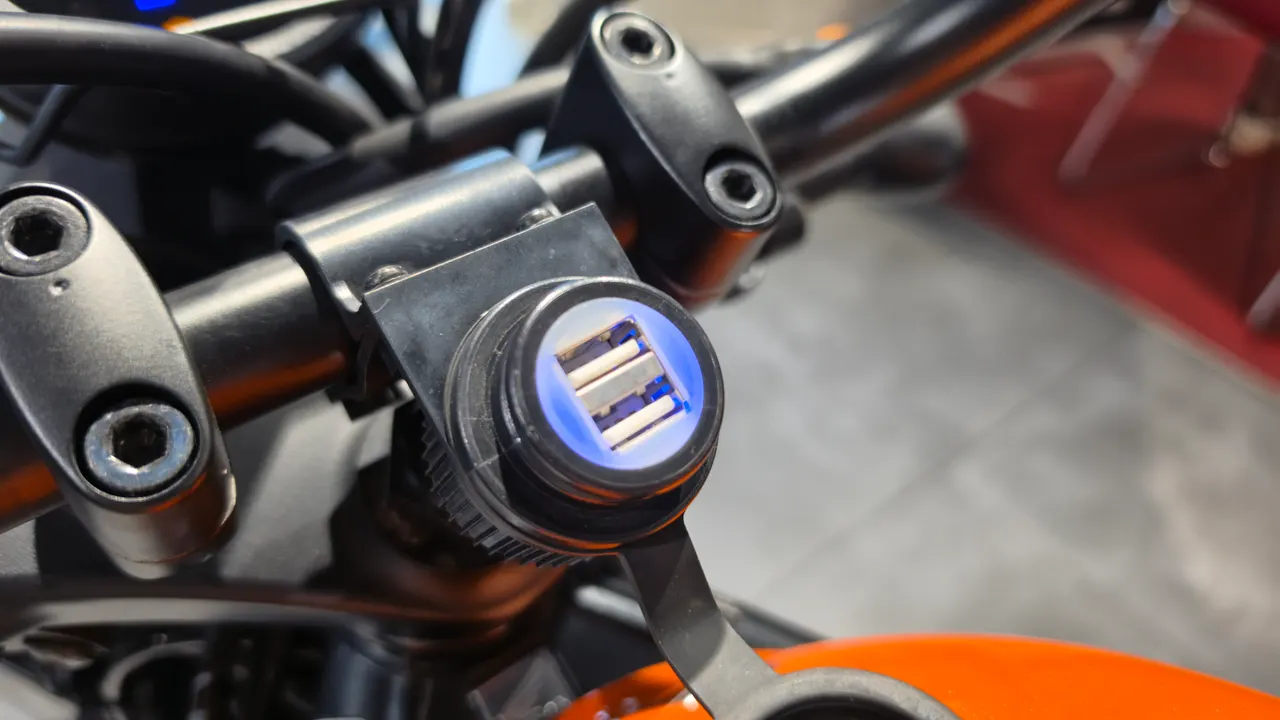 Cargador USB con luz azul en el manillar de una moto Honda CL500