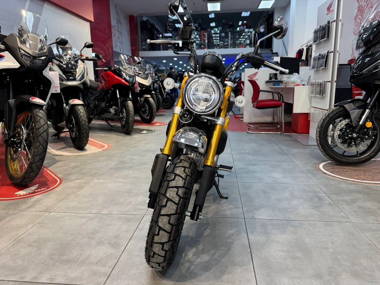 Honda Monkey amarilla con horquillas doradas en exposición