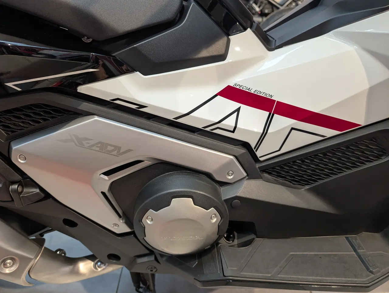 Detalle lateral de una Honda X-ADV Special Edition en blanco y negro con detalles rojos.