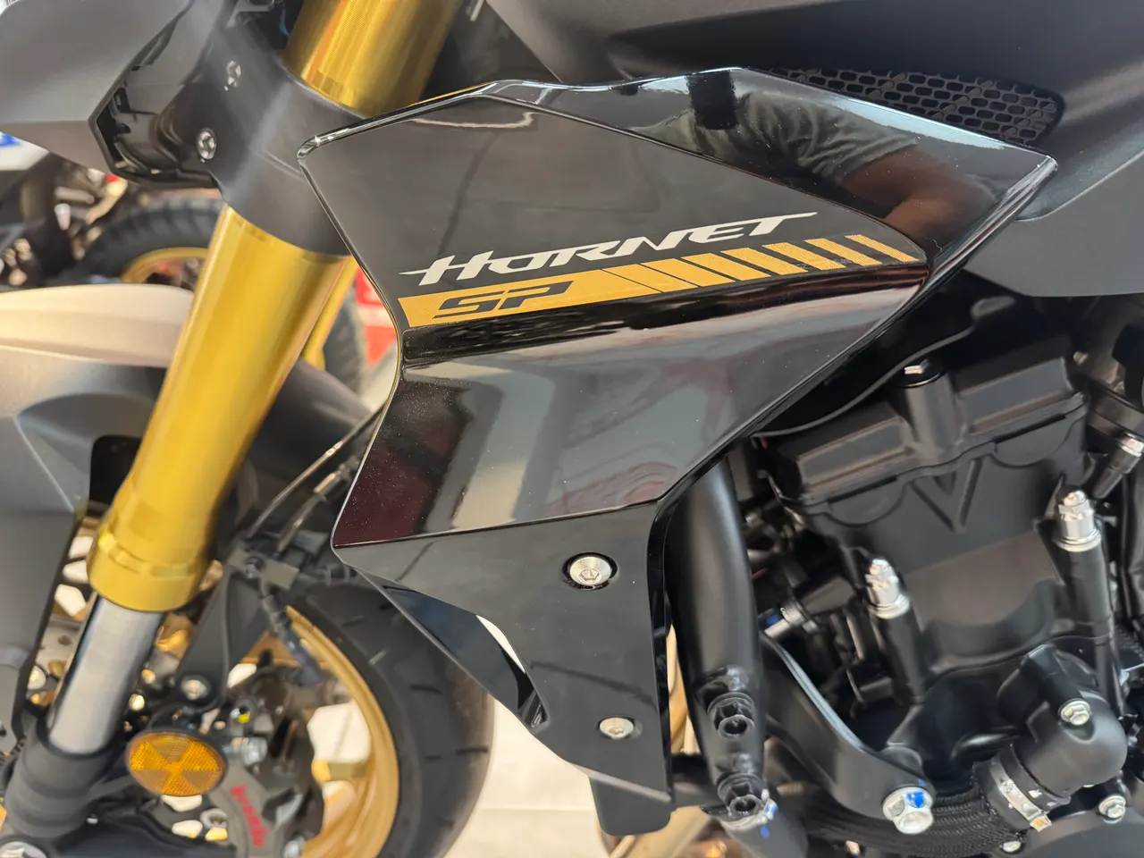 Detalle frontal de una moto Honda Hornet SP negra con detalles dorados.
