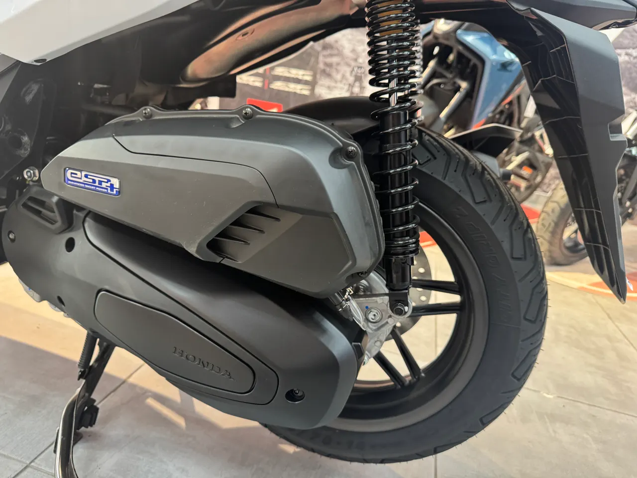 Detalle de la transmisión y rueda trasera de una Honda Forza 125 blanca.
