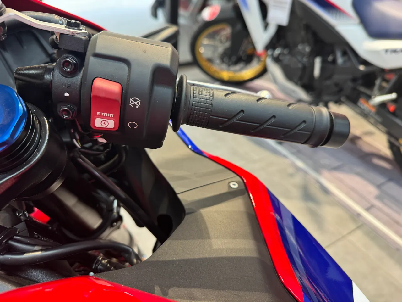 Detalle del manillar de una moto Honda CBR 600RR roja con el botón de arranque.