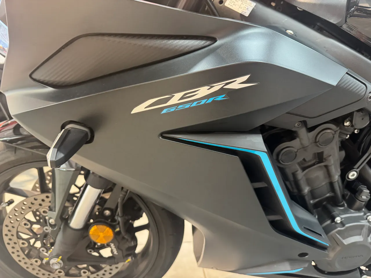 Detalle lateral de una moto Honda CBR650R negra con detalles azules