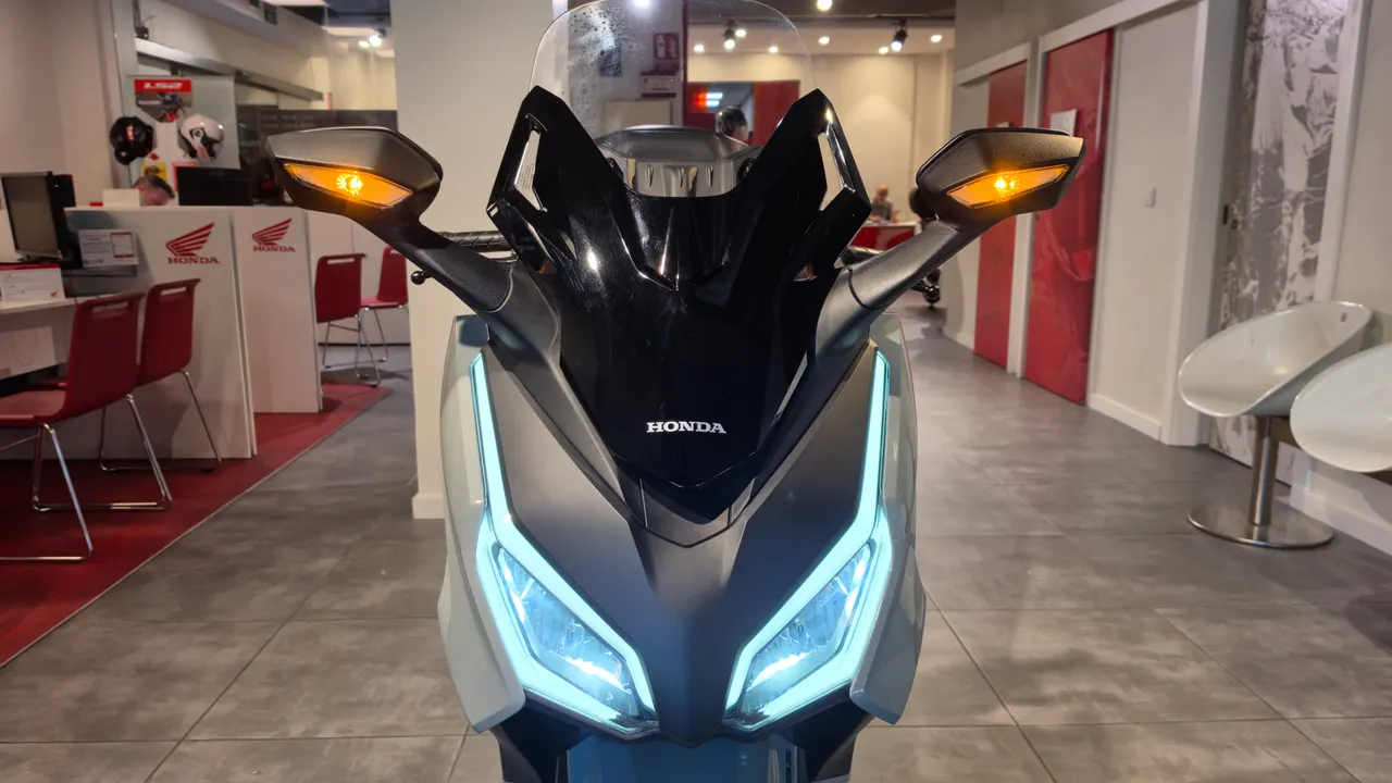 Frontal de scooter Honda Forza gris con luces LED encendidas y intermitentes naranjas
