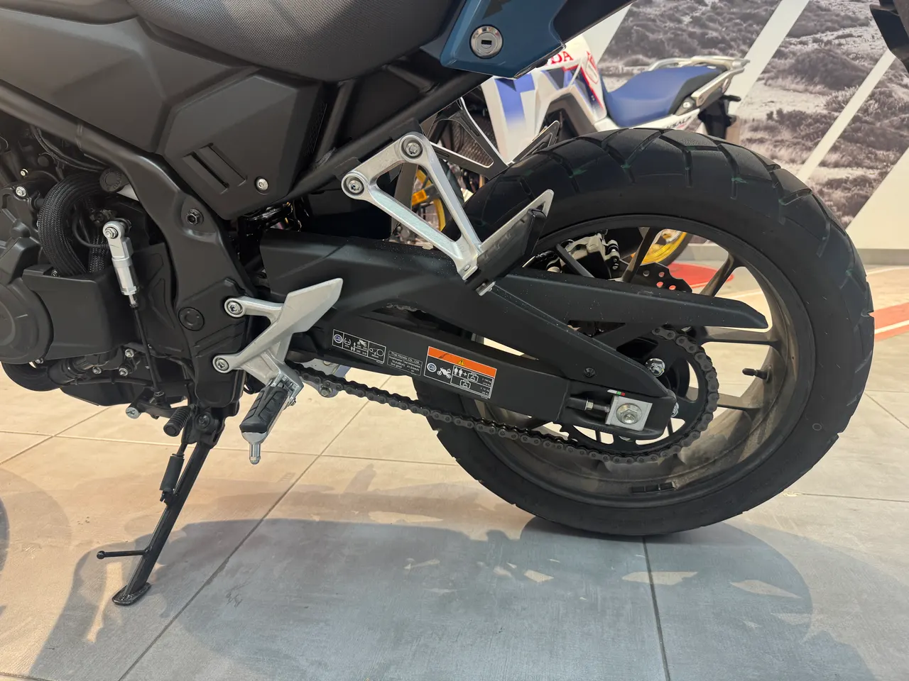 Parte trasera de la Honda NX500 E-Clutch azul oscuro con rueda y cadena