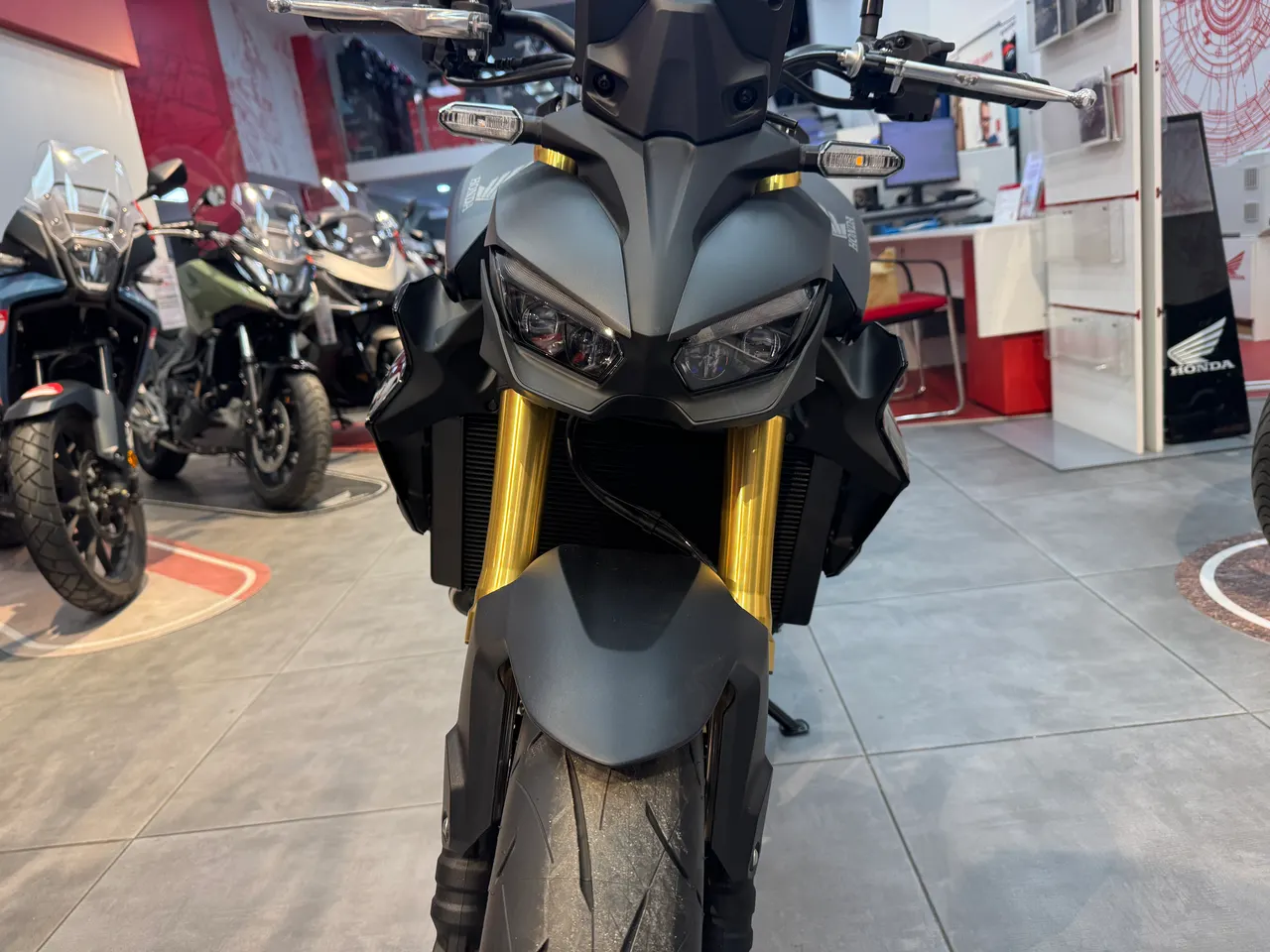Vista frontal de una moto Honda Hornet 1000 SP gris con horquillas doradas.