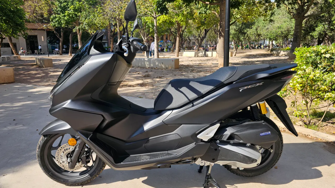 Scooter Honda PCX 125 negro mate aparcada en un parque