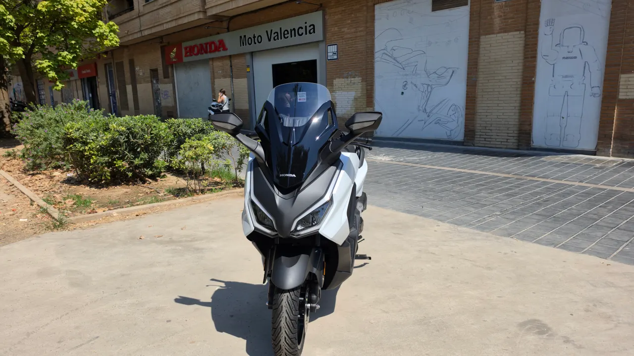 Honda Forza 125 blanca estacionada frente a concesionario Honda