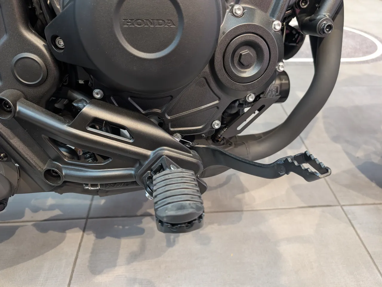 Detalle del motor, estribera y palanca de cambios de una HondaRebel 500 negra
