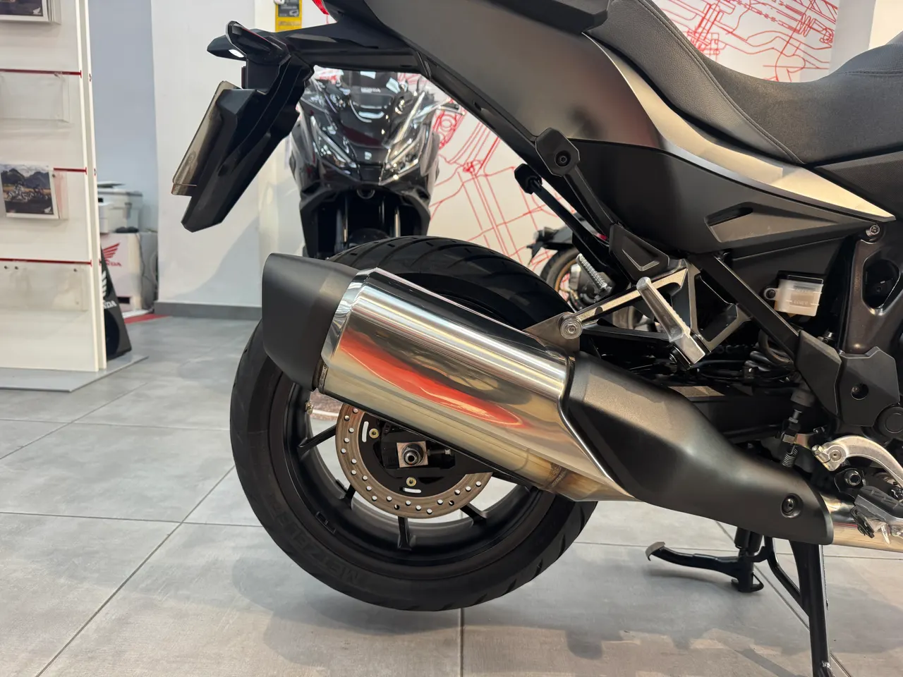 Vista detallada del escape cromado y la rueda trasera de una motocicleta negra