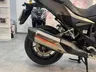 Vista detallada del escape cromado y la rueda trasera de una motocicleta negra