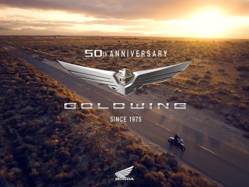 una carretera en un atardecer con una honda goldwing 50 aniversario conduciendo por la carretera